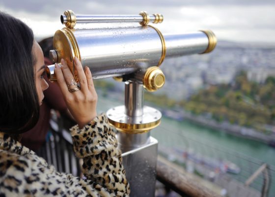 woman looking through a telescope during daytime