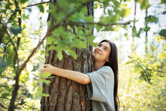 A,Woman,Stands,In,A,Vibrant,Forest,,Lovingly,Embracing,A